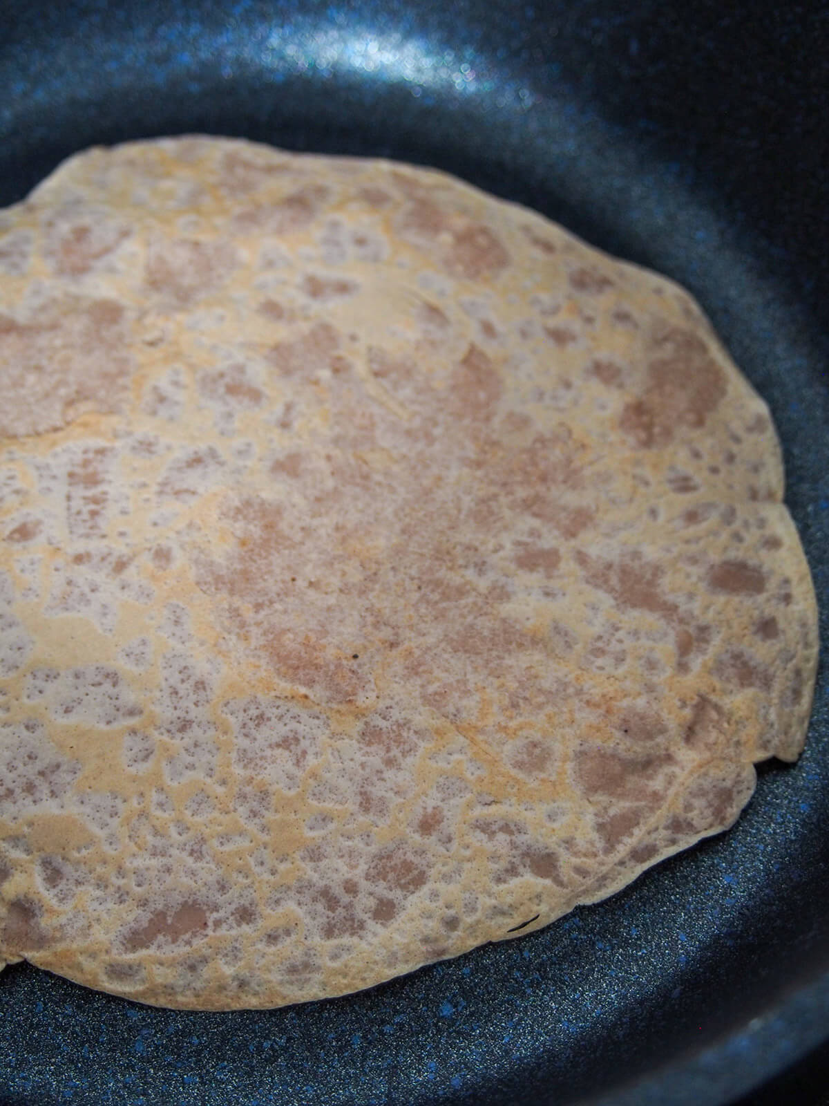 a crepe in skillet with first cooked side up
