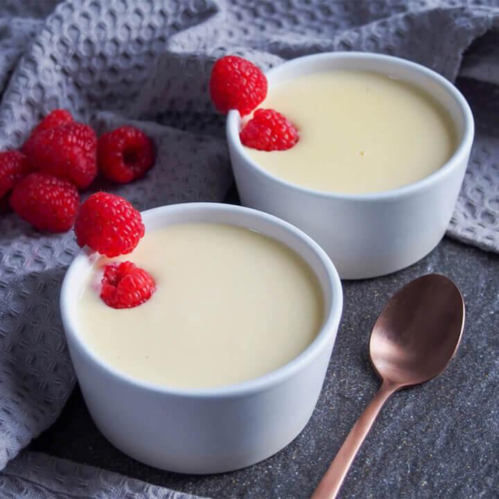 two bowls of creme Anglaise with raspberries as decoration