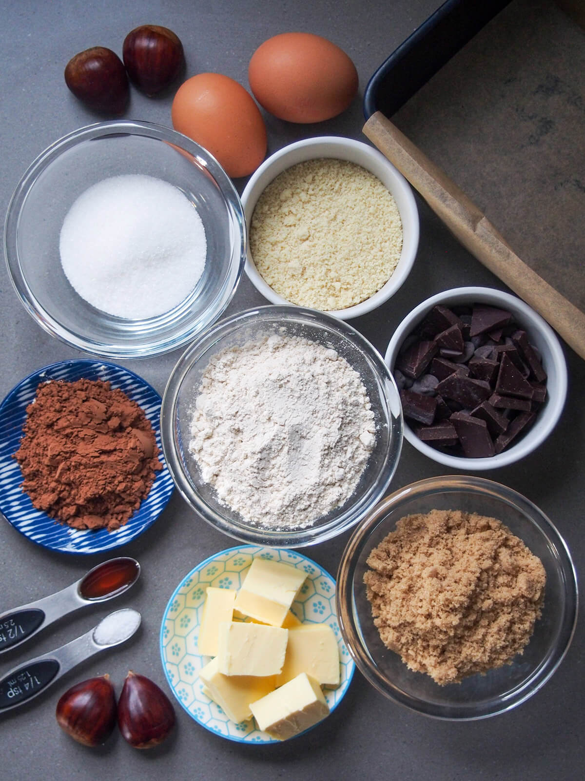 bowls with sugar, chocolate, flours, cocoa powder and butter plus eggs above