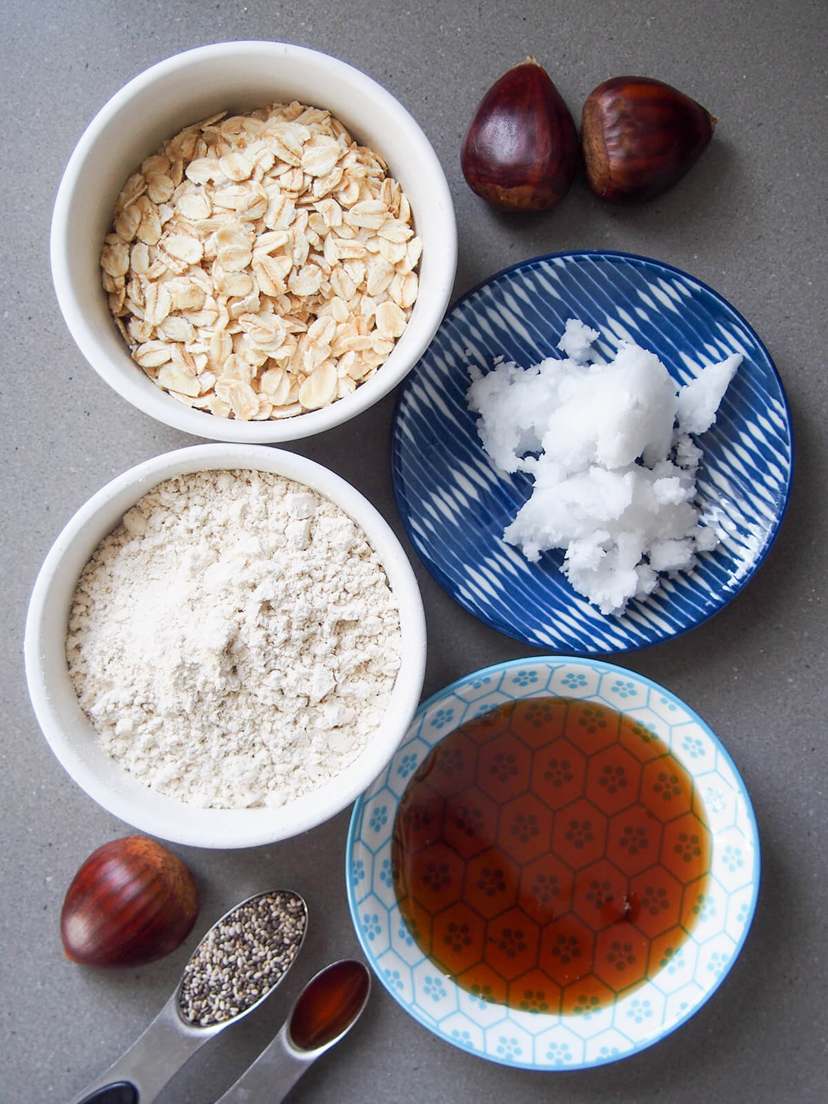 bowls with oats, maple syrup, coconut oil, coconut flour, and spoons with chia and vanilla