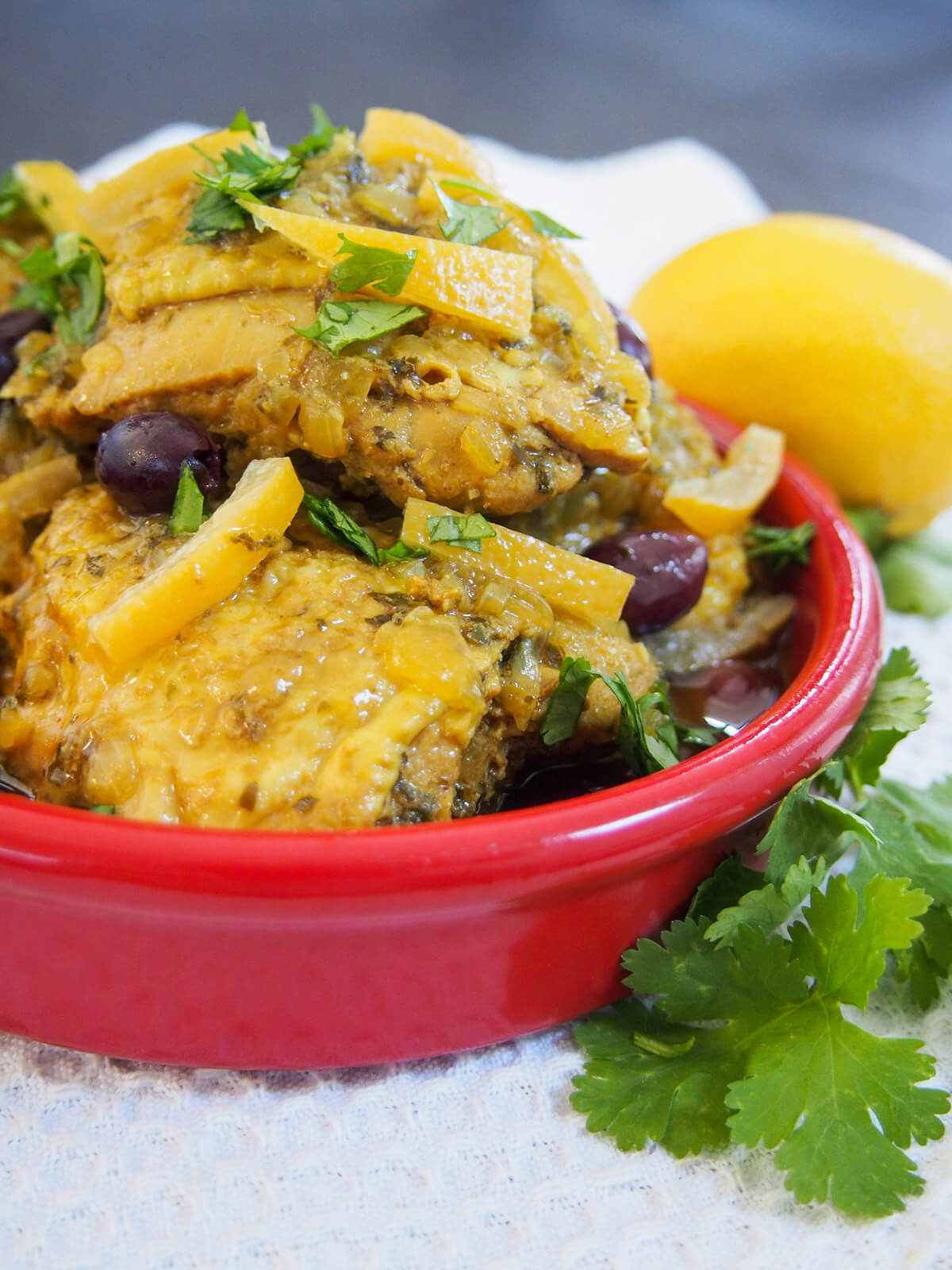 side view of Chicken tagine with preserved lemons and olives with herbs and lemon to side