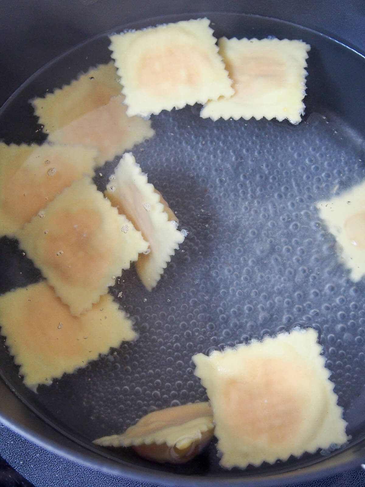 cooking ravioli in pan of boiling water