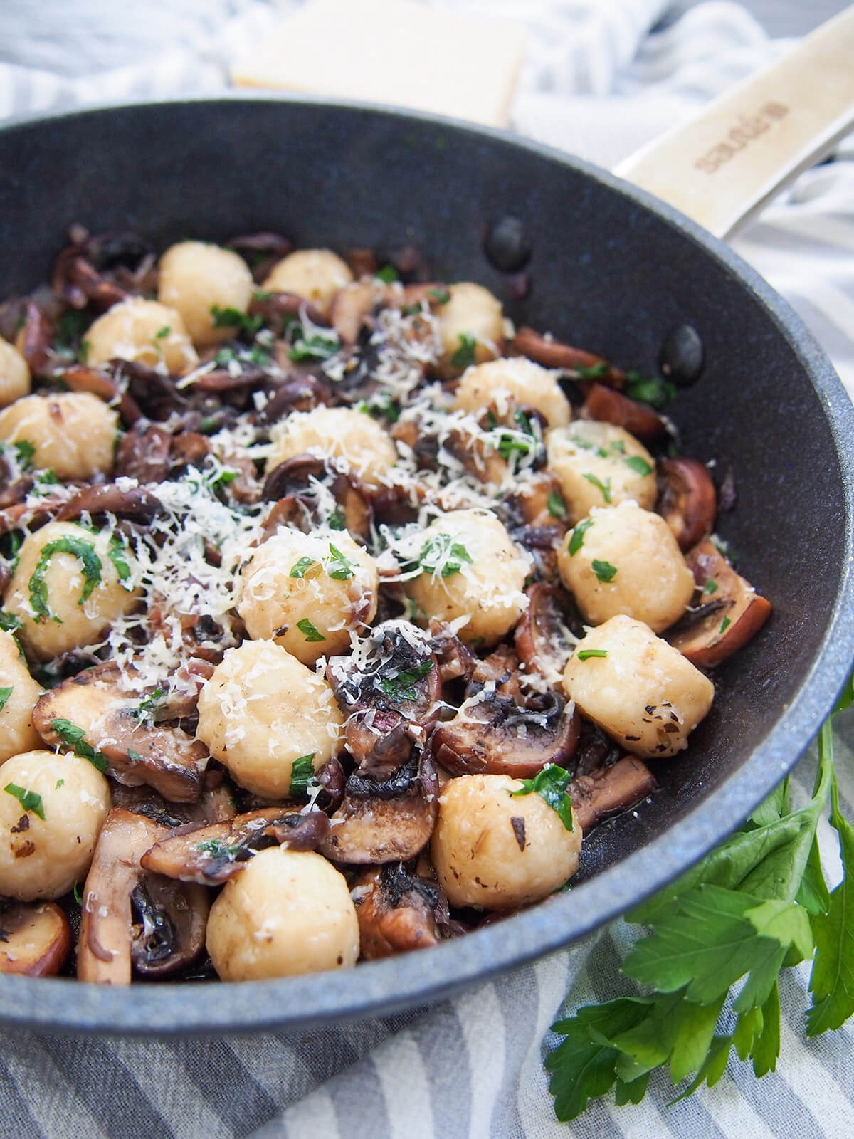 skillet with mushroom gnocchi and some parsley below skillet