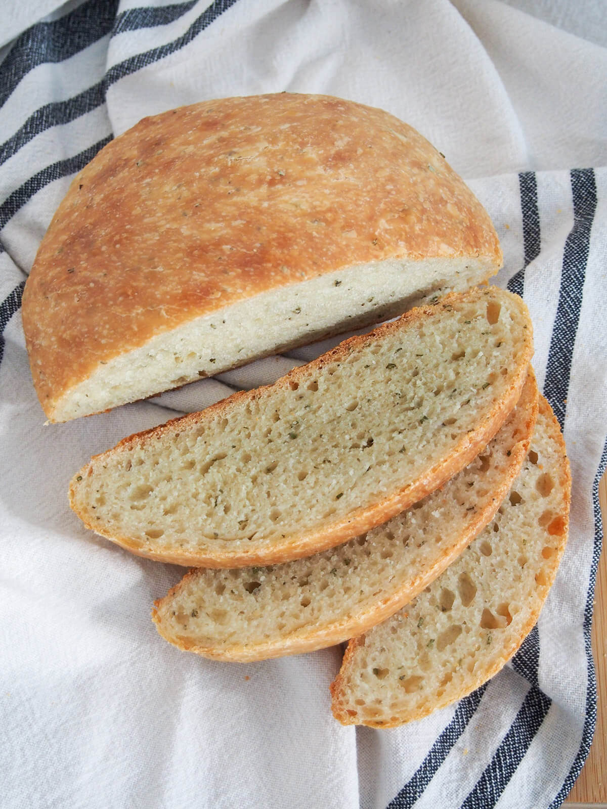 no knead olive oil rosemary bread with slices fanned out in front of rest of loaf