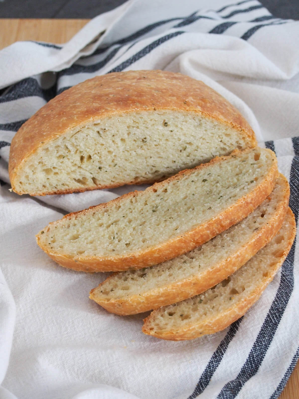 No knead olive oil rosemary bread with slices in front of rest of loaf