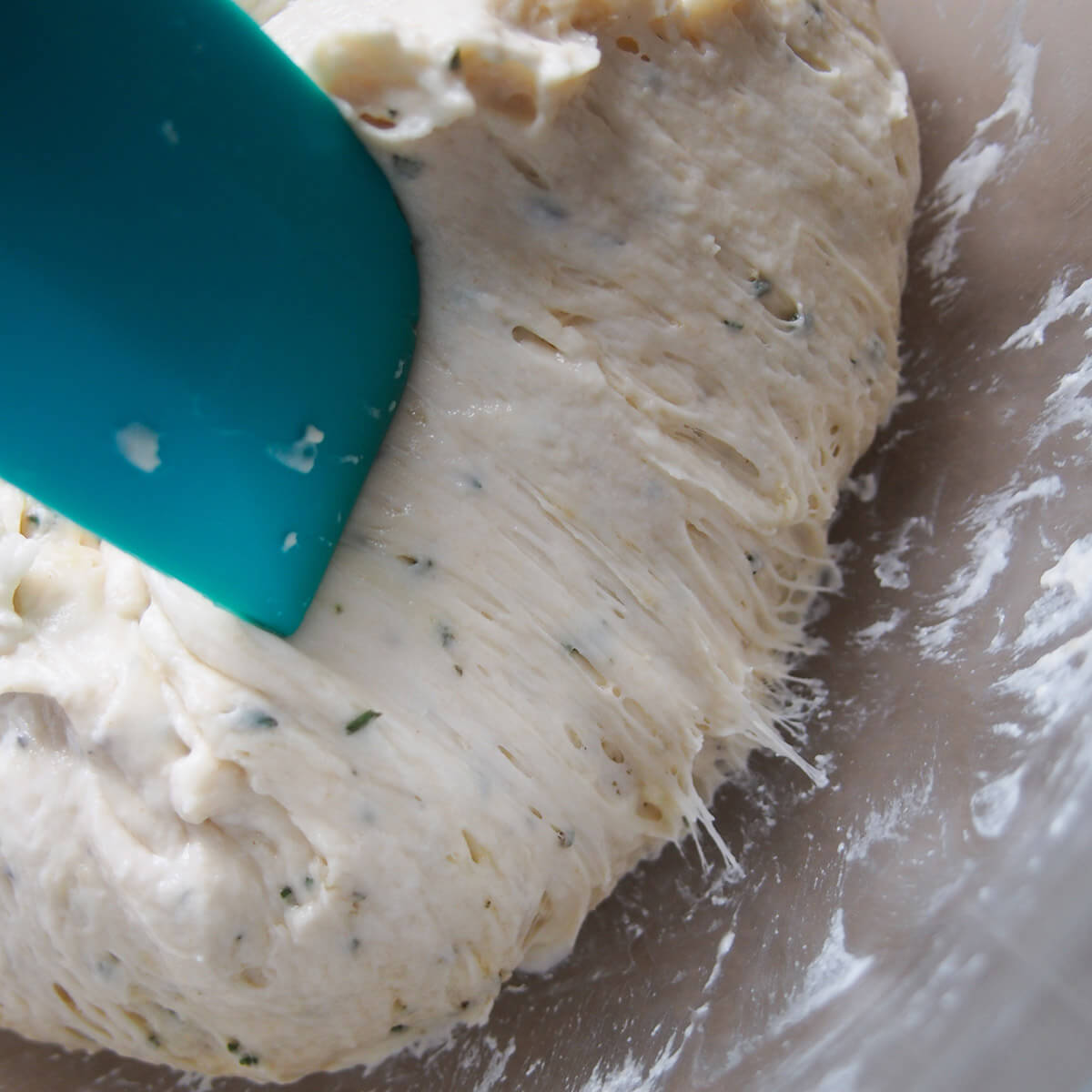 scraping dough away from side of bowl showing gluten strands