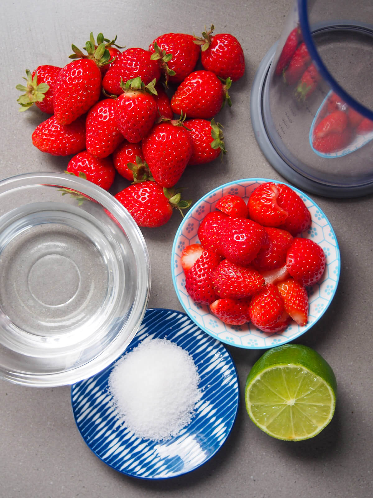 bowls with strawberries, water, sugar and cut lime below