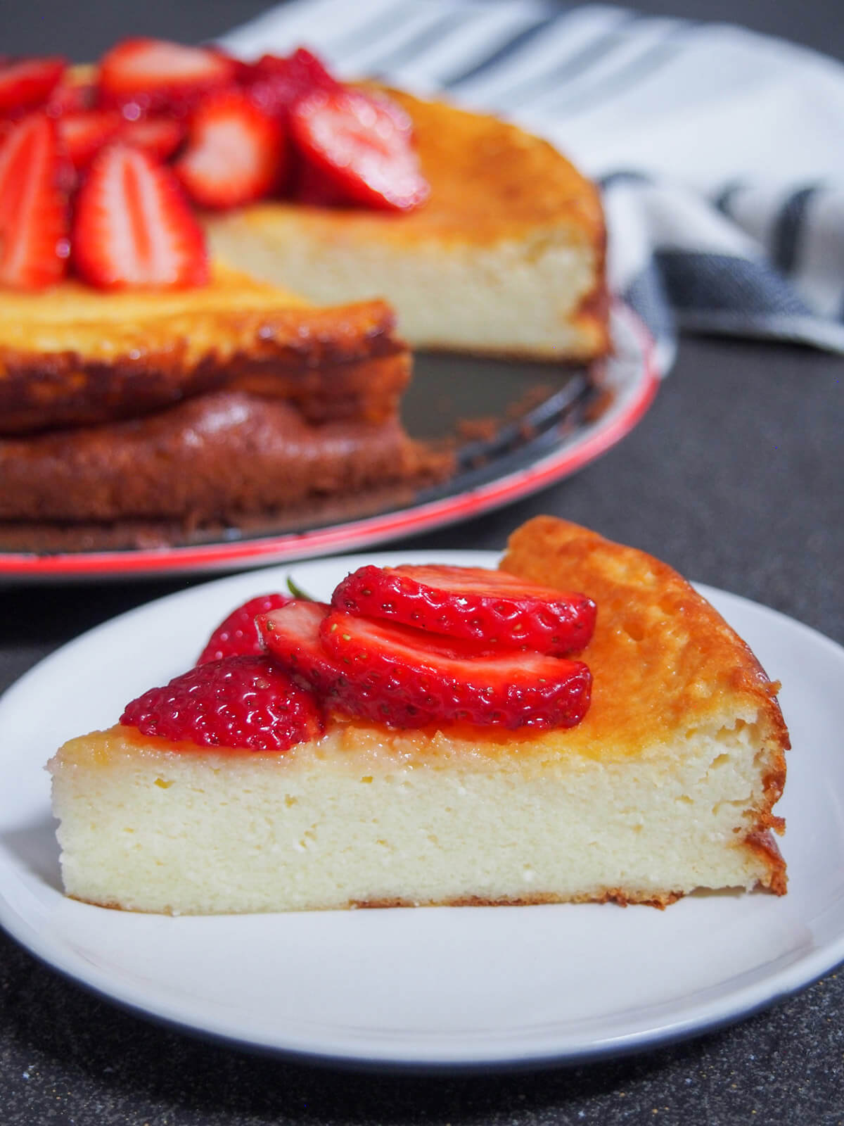 slice of Swedish ostkaka with partial view of rest of cheesecake behind