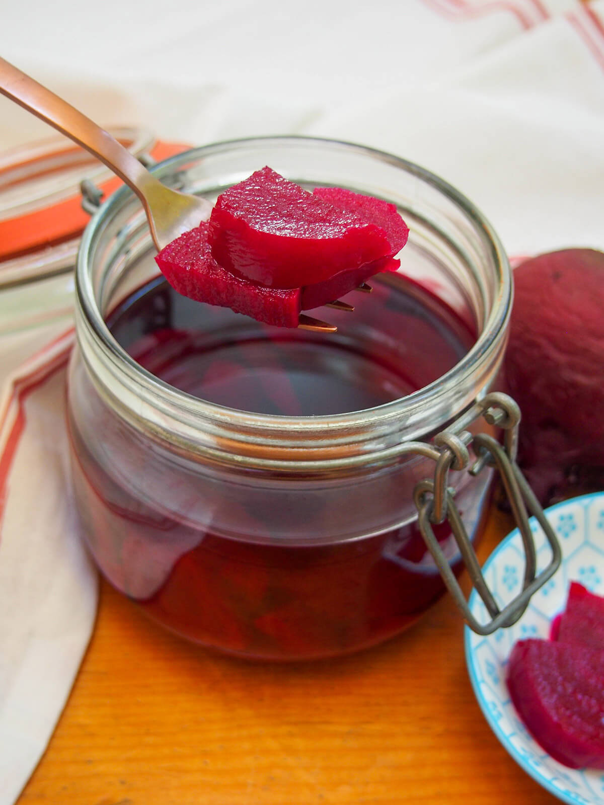 These Swedish pickled beets are so easy to make and have a great sweet-tart flavor. You can enjoy them on their own, to top sandwiches or mixed in salads. They're a popular side for good reason. holding slices of Swedish pickled beets over jar with more