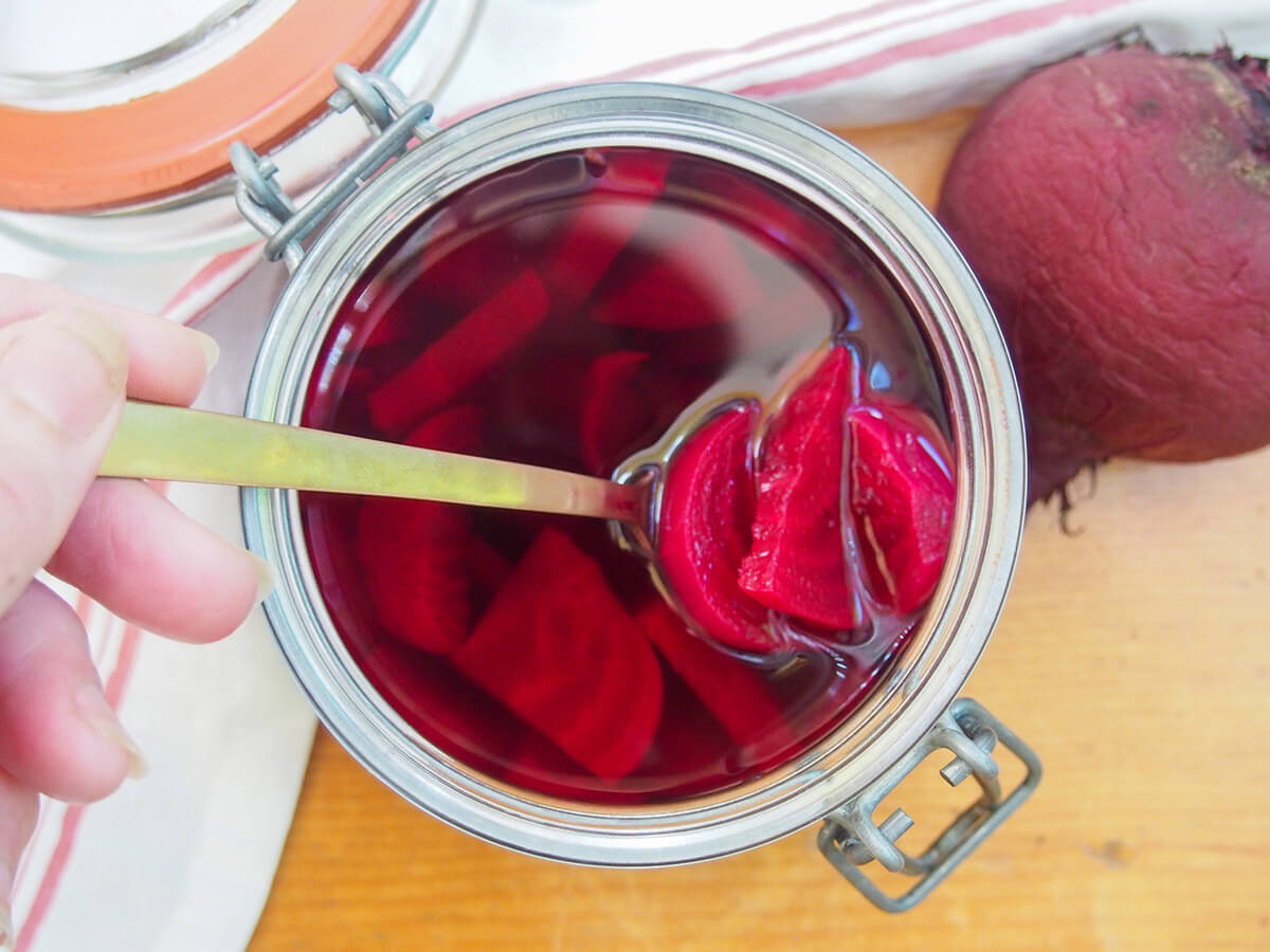 These Swedish pickled beets are so easy to make and have a great sweet-tart flavor. You can enjoy them on their own, to top sandwiches or mixed in salads. They're a popular side for good reason. overhead view of jar of pickled beets with a few slices lifted on fork