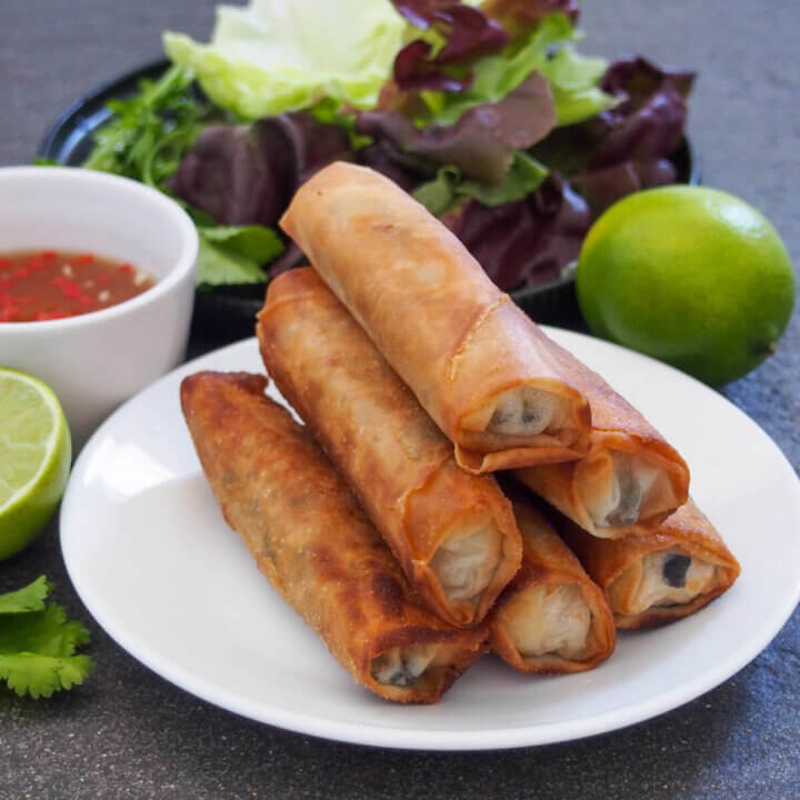 plate of Vietnamese fried spring rolls with lime and lettuce leaves behind