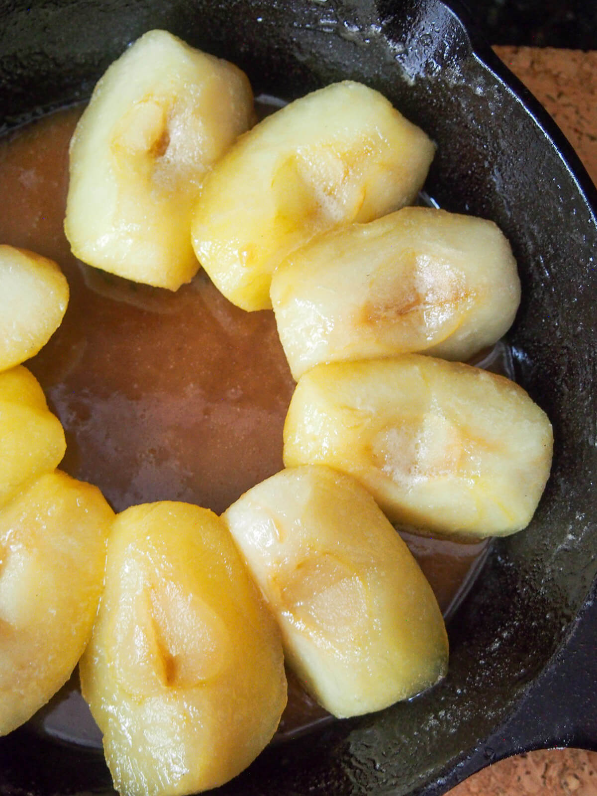 adding apples into caramel for apple tarte tatin adding apples to caramel in skillet