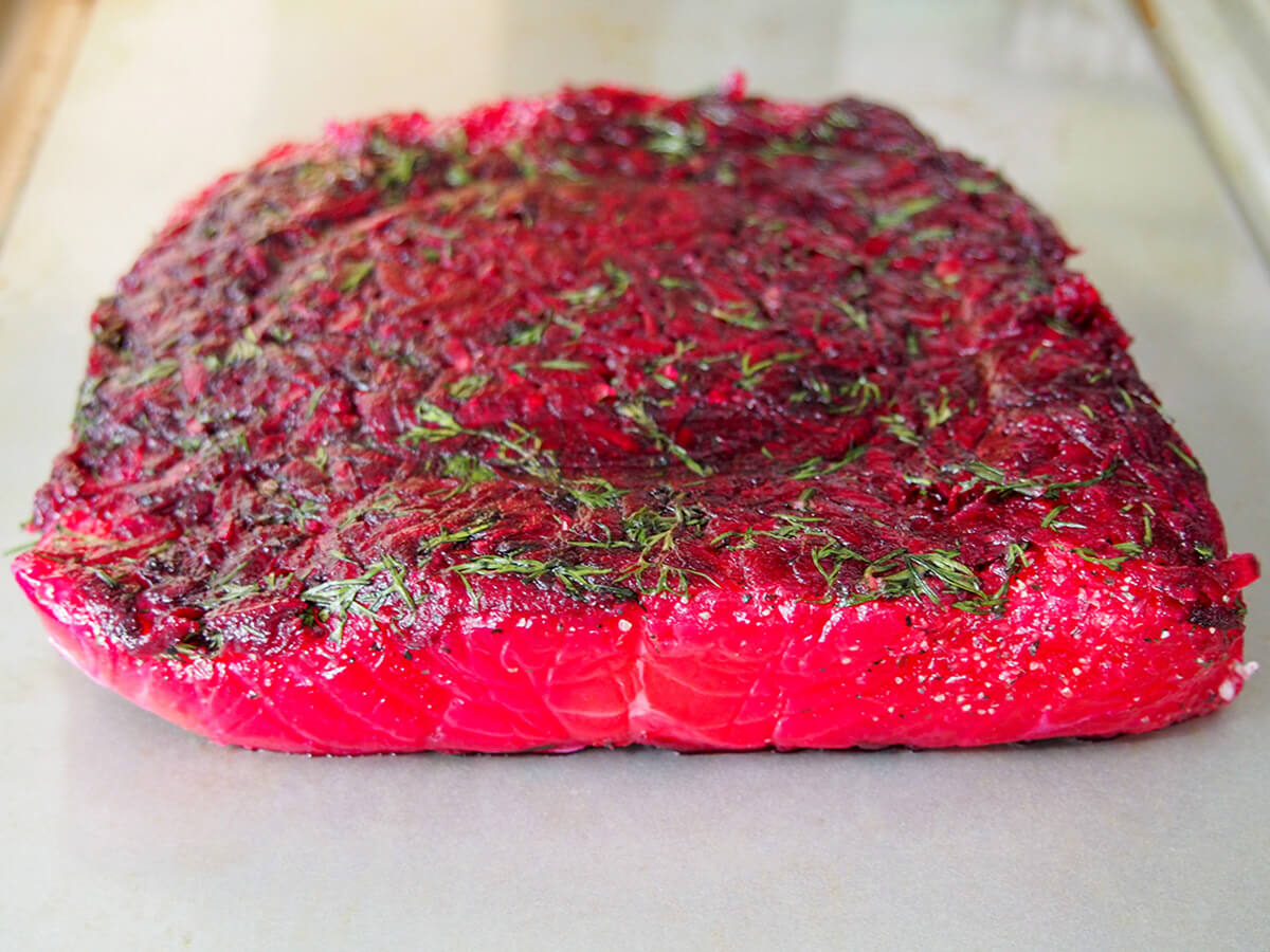 beet cured salmon out of cure piece of salmon covered in beet cure mixture after curing