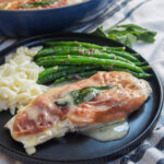 part view of plate of chicken saltimbocca with green beans and some sage behind plate