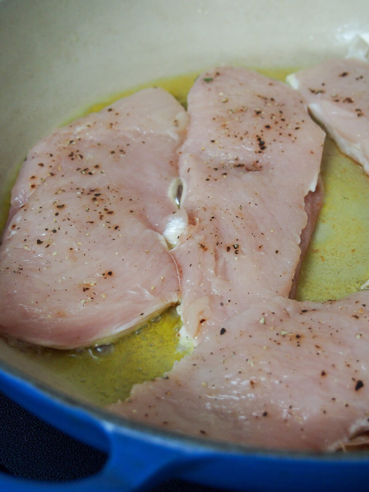 chicken cooking in skillet with uncooked side up