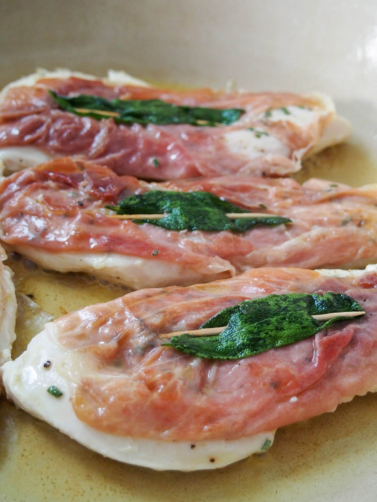 cooking chicken with prosciutto and sage on top