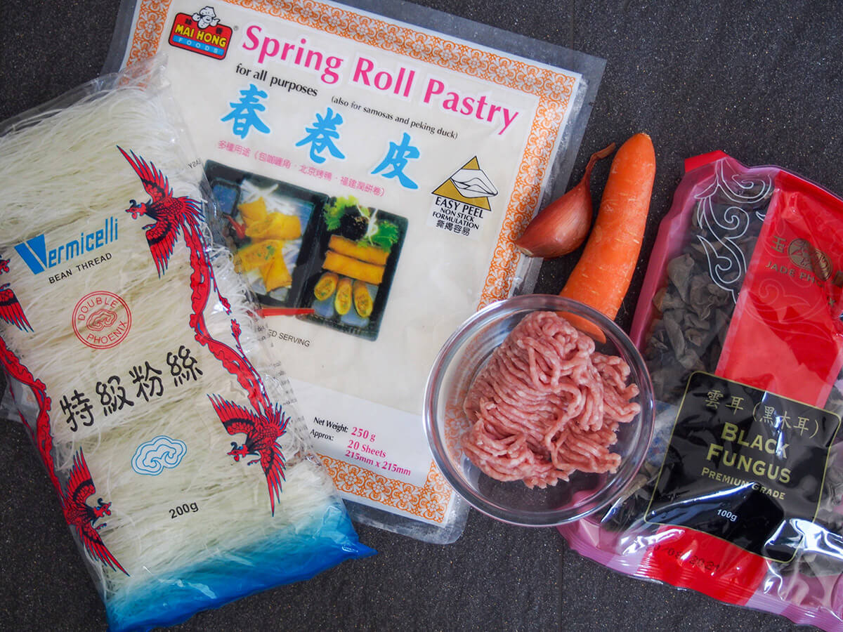 packets of spring roll wrappers, vermicelli noodles, wood ear mushrooms and bowl with pork, carrot and shallot above