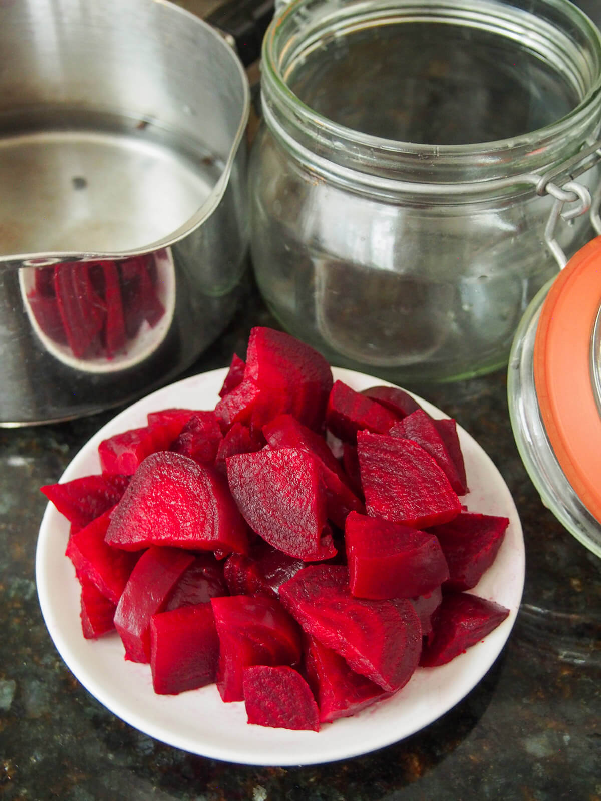 making Swedish pickled beets plate of diced beets with jar behind and pan with peppercorns in liquid
