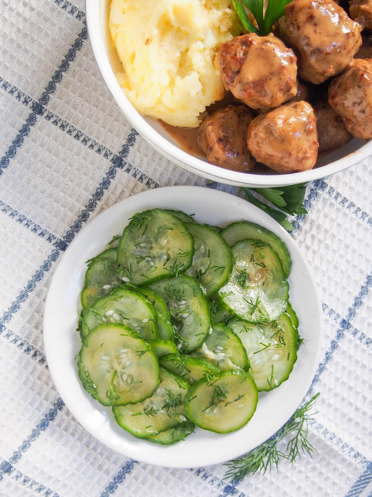 plate of pressgurka Swedish cucumber below bowl with Swedish meatballs and mashed potato