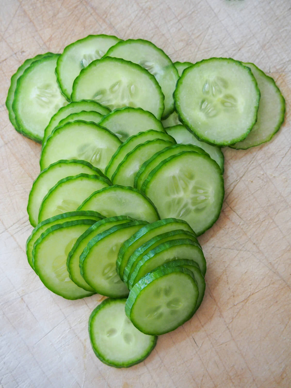 thinly sliced cucumber slices on chopping board