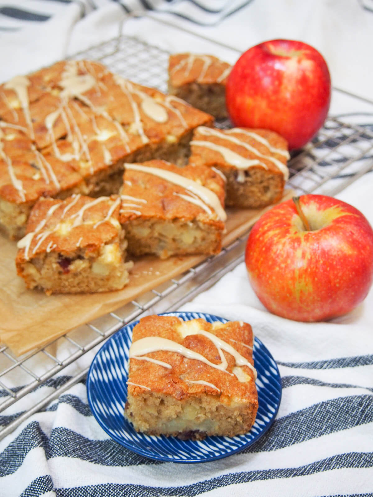 This apple snack cake is easy to make, packed with chunks of apple and gently spiced. It has a wonderful balance of sweetness, tender buttery cake and fruitiness. It's always incredibly popular with all who try it, so make sure you do soon, too! pieces of apple snack cake with apples to side