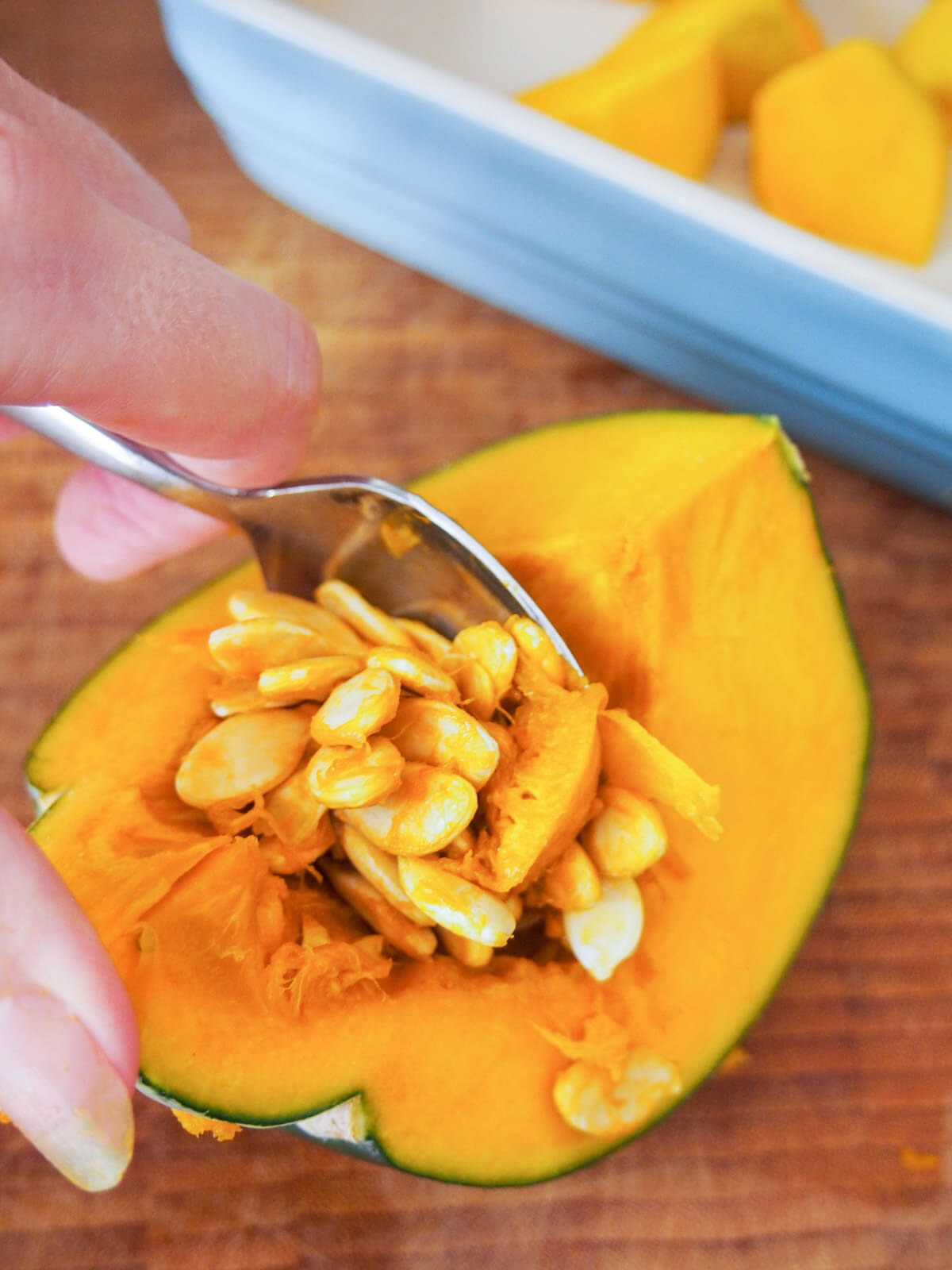 scooping seeds from piece of squash
