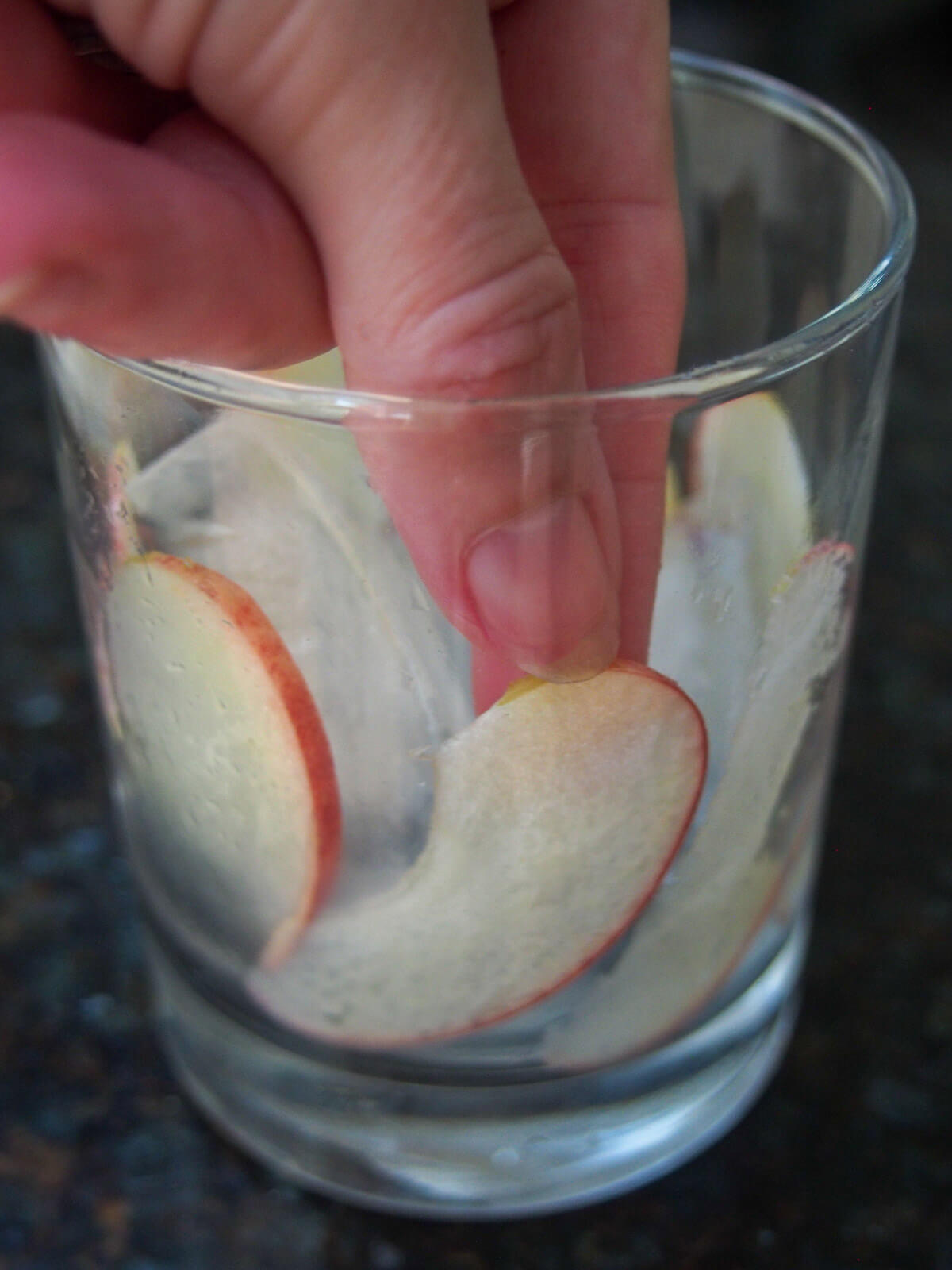 placing thin slices of apples around glass