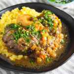 close up of beef osso bucco on plate with risotto
