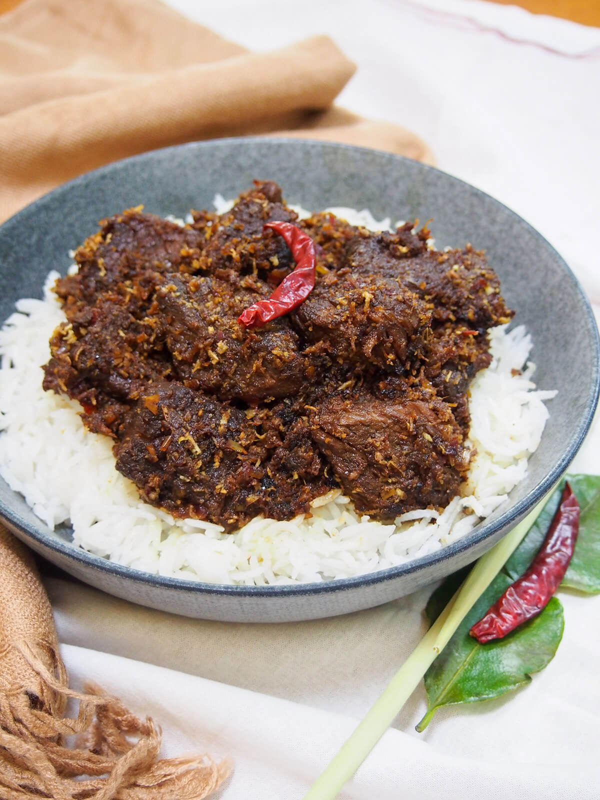 bowl of beef rendang topped with a red chili