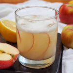 glass of calvados sour with cut lemon and apple to side