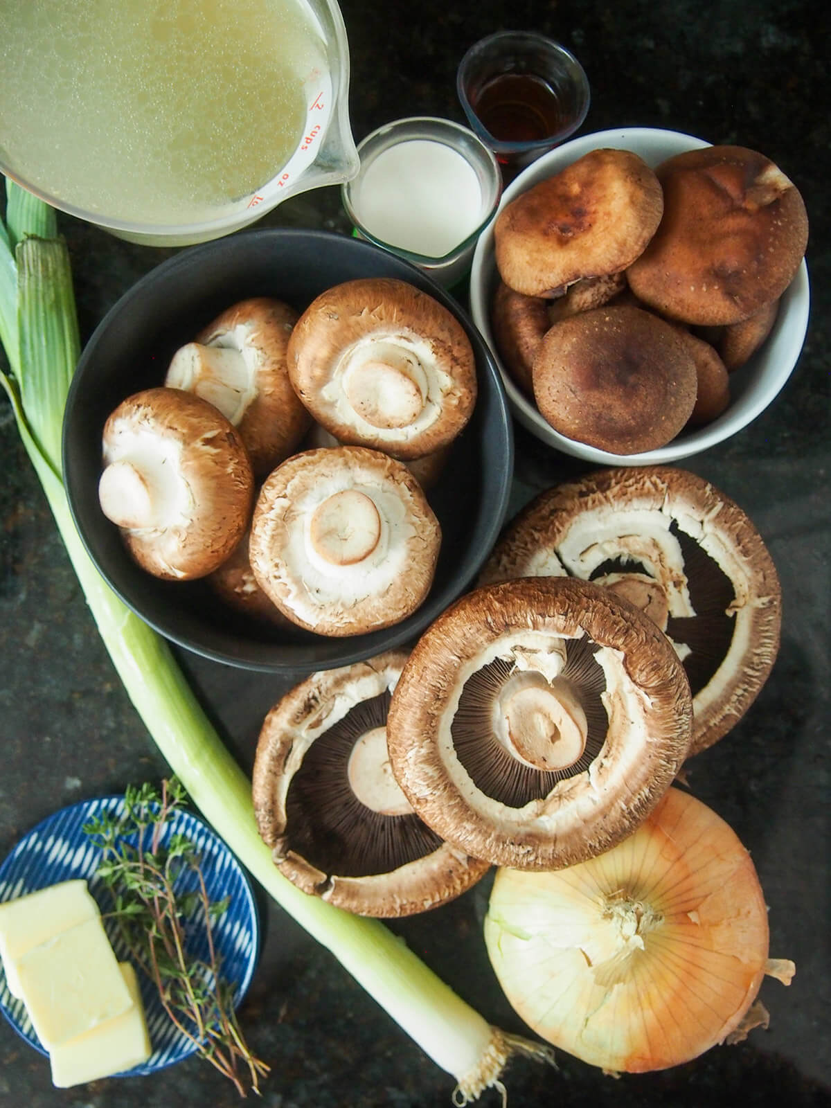 wild mushroom soup ingredients piles of mushrooms, stock, onion, leek and cream to side