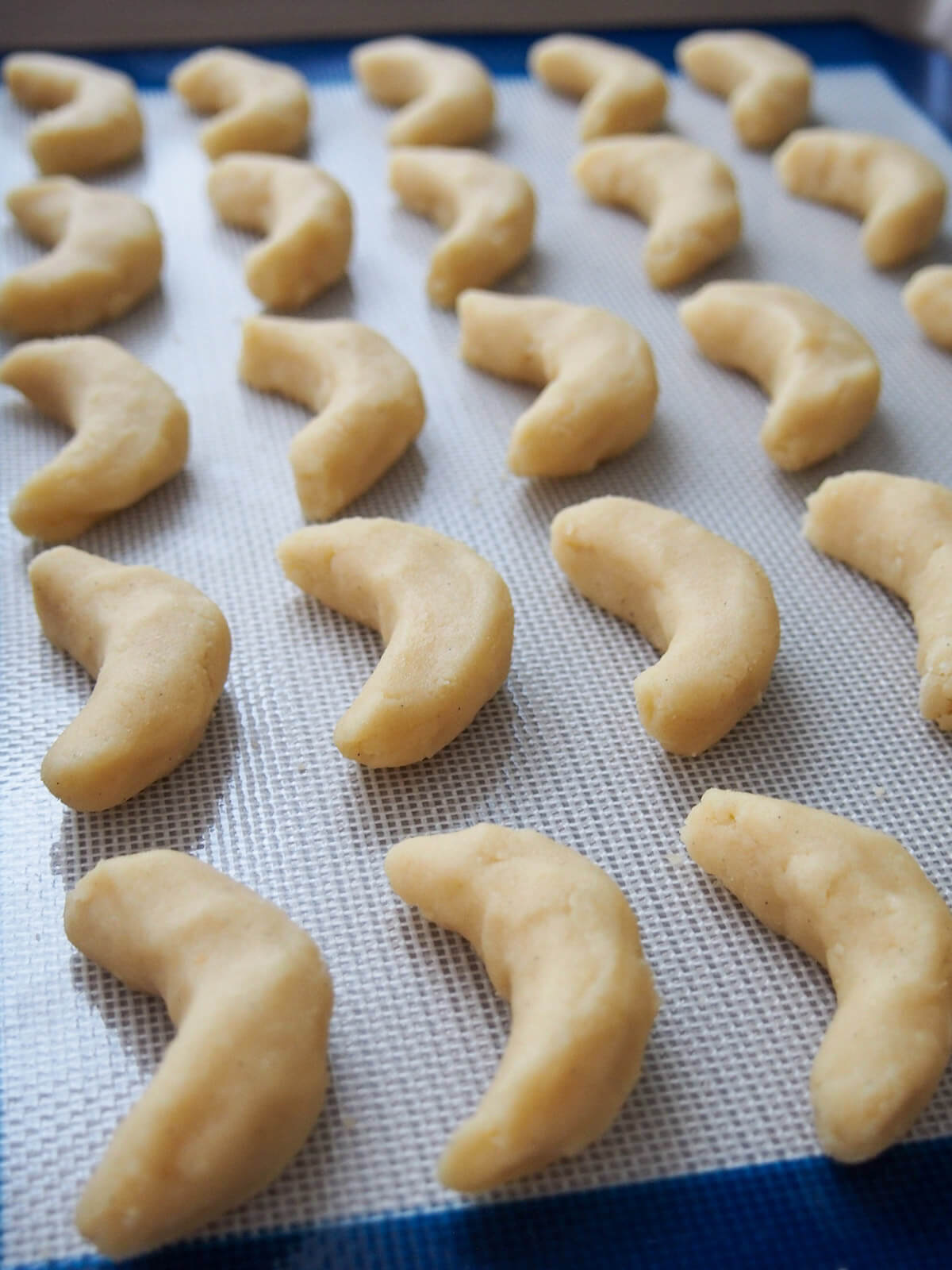 vanillekipferl crescent cookies lined up on baking sheet before baking formed vanilla crescent cookies on lined baking sheet before baking