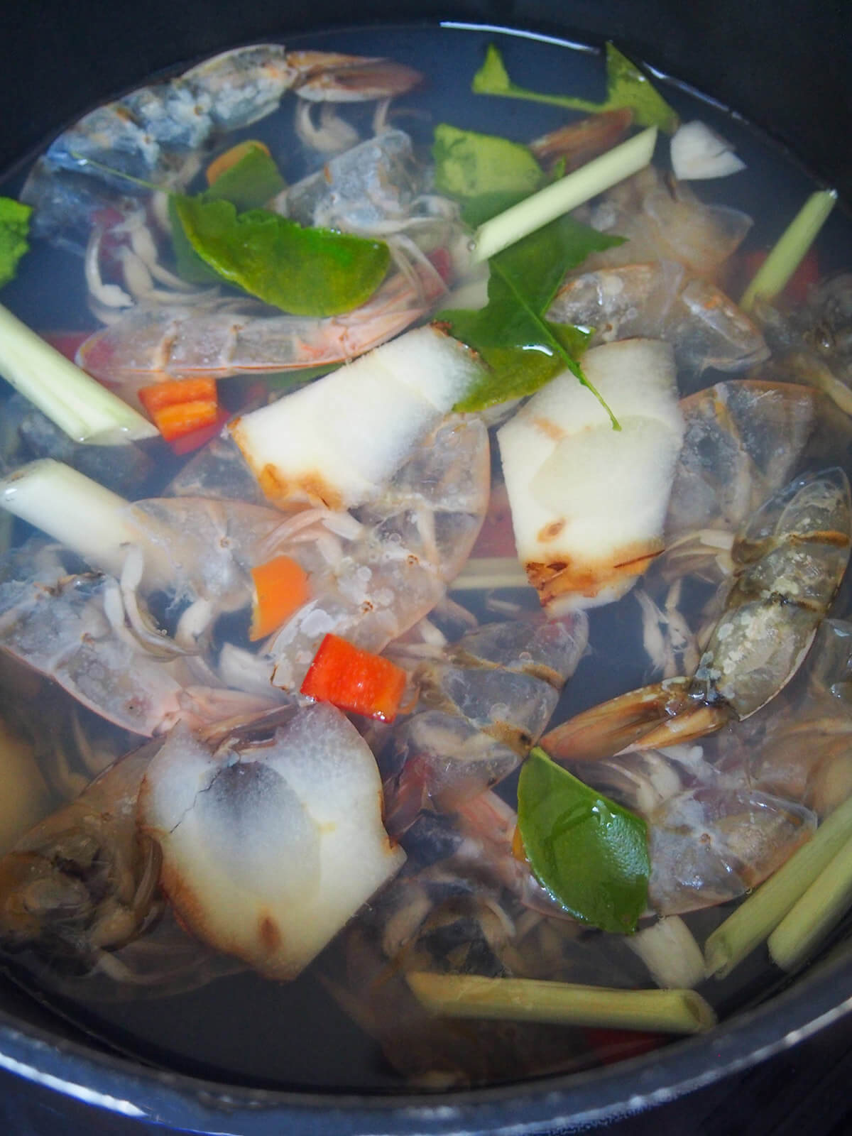 shrimp shells, lemongrass , galangal and lime leaves in pot with water to make broth base