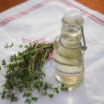 bottle of thyme simple syrup with bunch of thyme to side