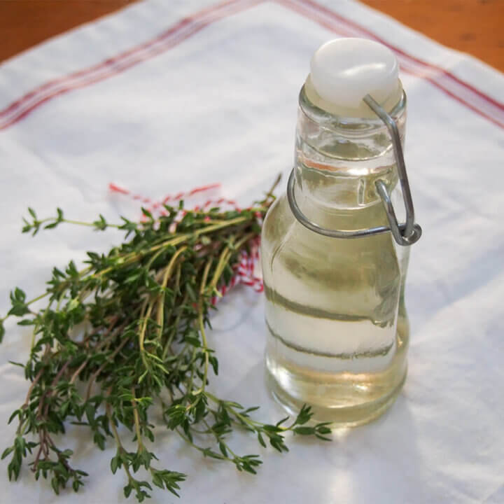 bottle of thyme simple syrup with bunch of thyme to side