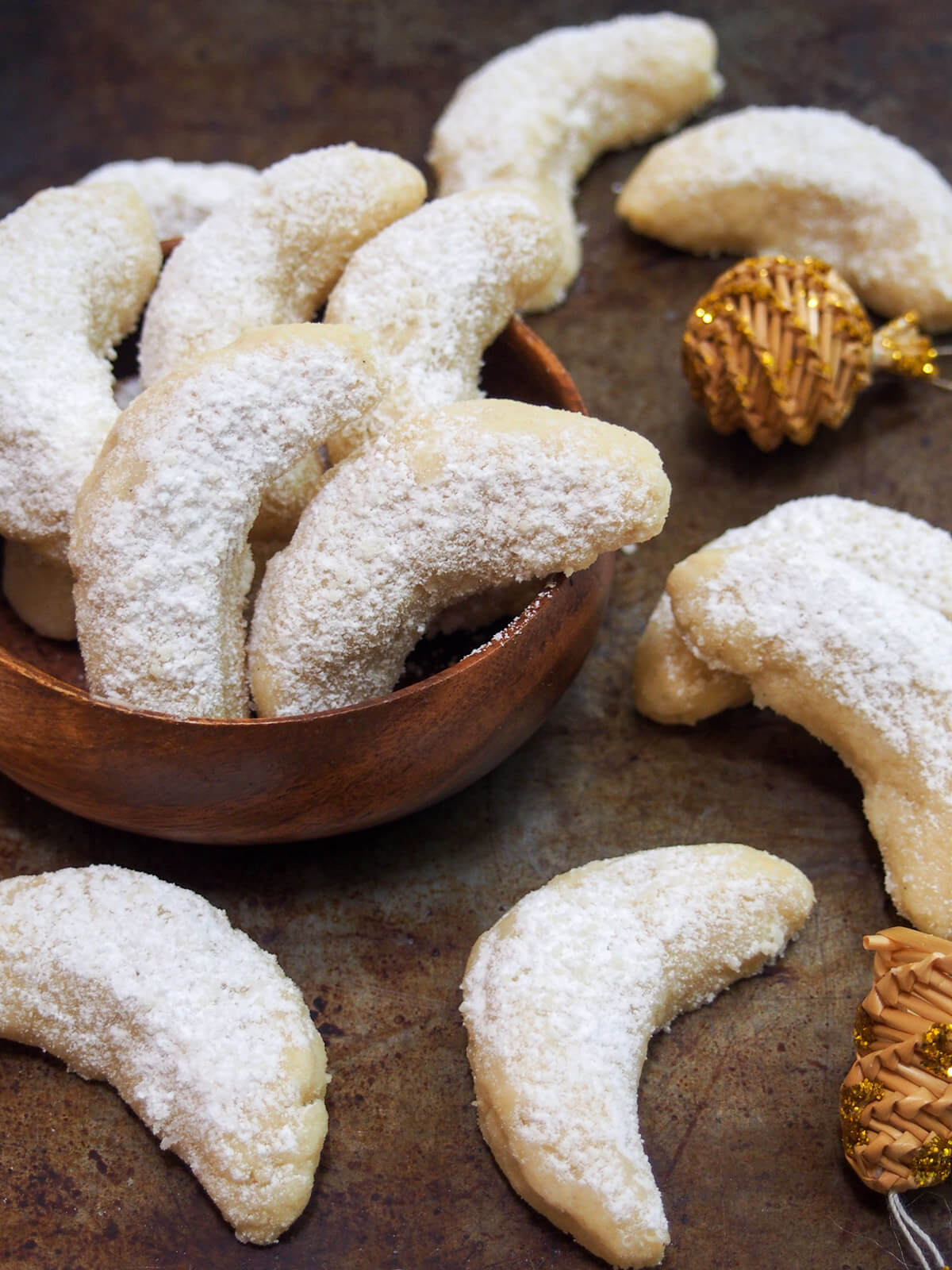 Vanillekipferl (vanilla crescent cookies) are a classic Austrian/German cookie with a delicate vanilla flavor. They melt in your mouth and are a perfect addition to a seasonal cookie plate. some vanillekipferl vanilla crescent cookies with decorations to side
