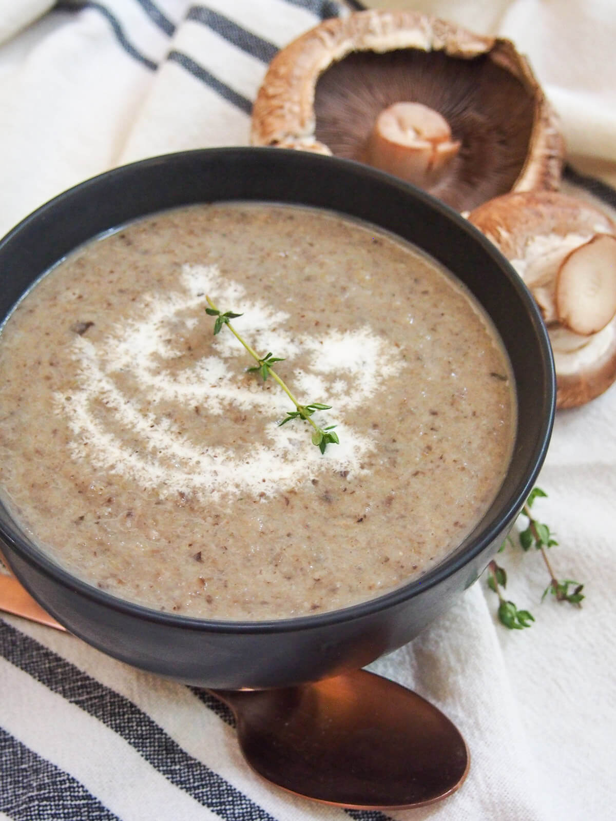 This wild mushroom soup uses a blend of mushrooms to add more depth of flavor, but with all that wonderful earthiness and smooth creaminess you would expect. It's easy to make, comforting and delicious. bowl of soup from side with mushrooms behind