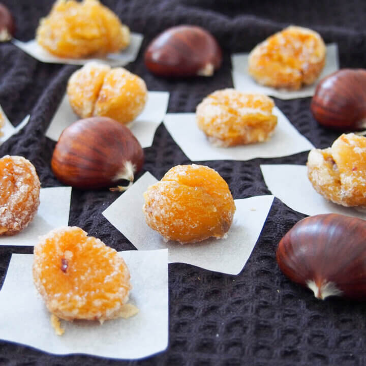 some marrons glaces on pieces of paper with whole chestnuts in between