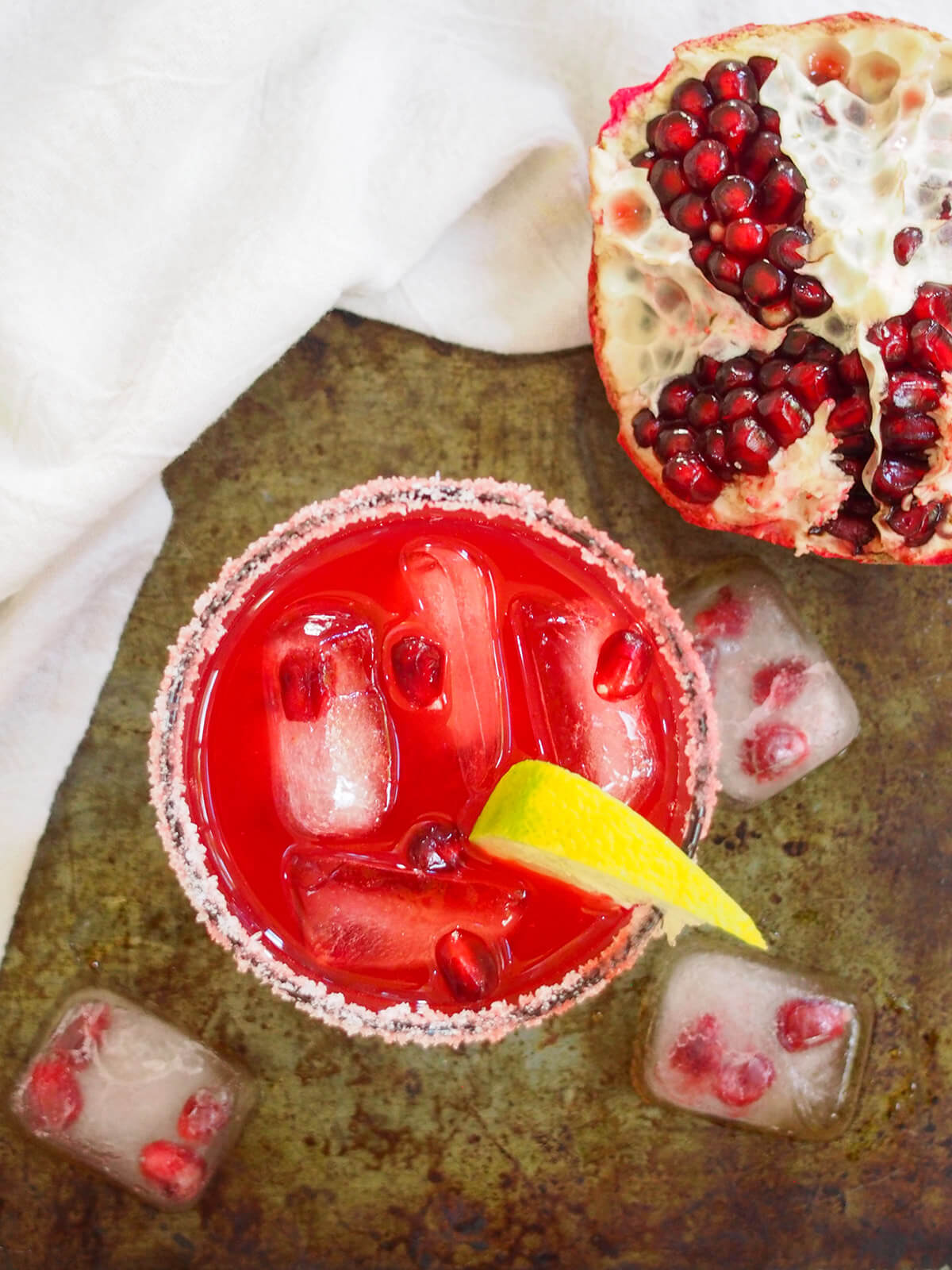 glass of pomegranate margarita form overhead with open pomegranate above glass