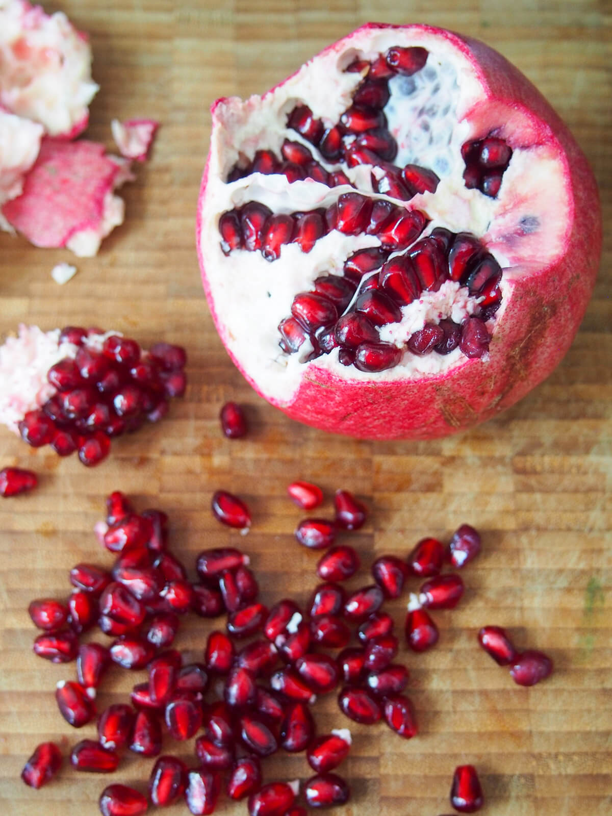 opening up a pomegranate with arils below