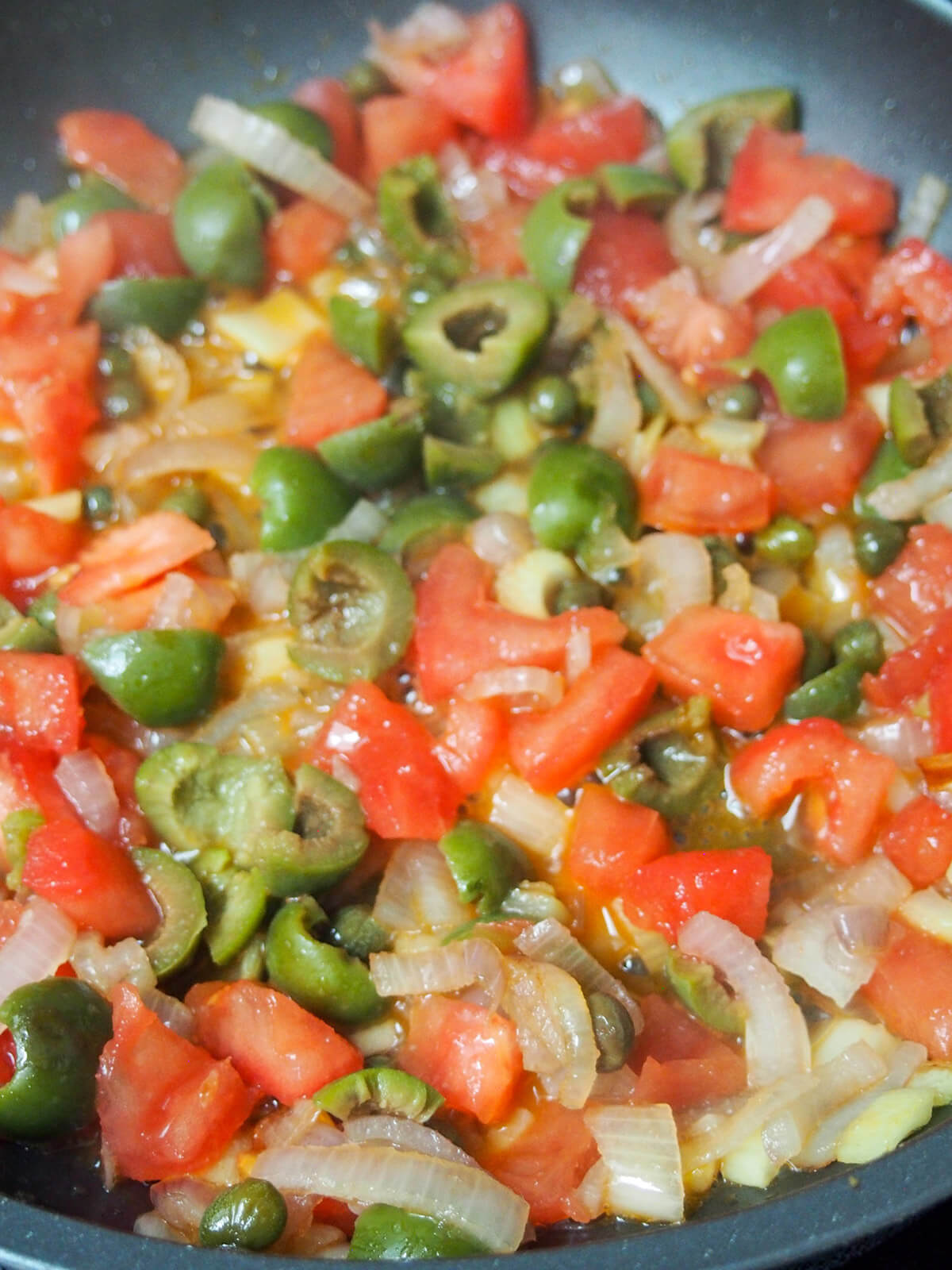 skillet with onion, tomato, capers and olives
