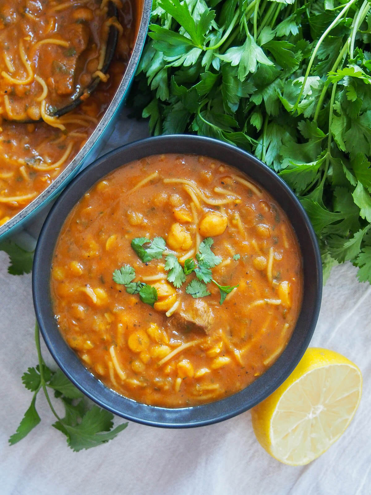 bowl of harira soup with herbs above bowl