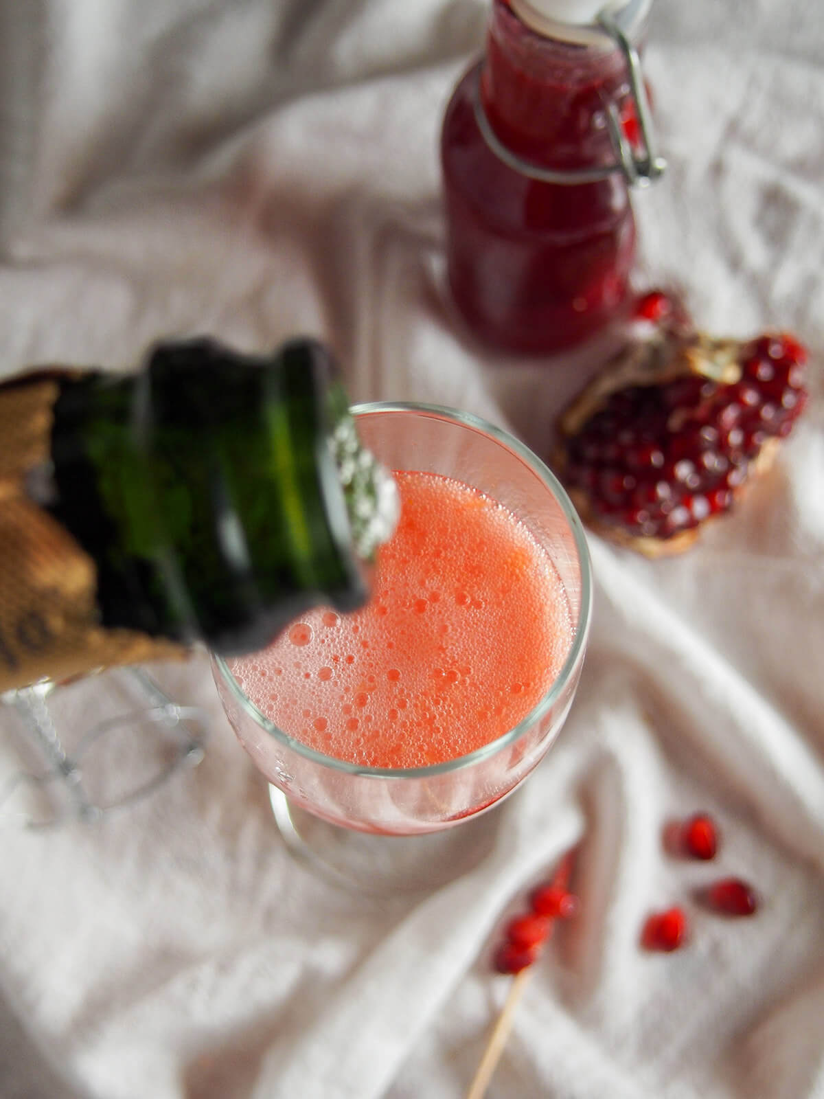 adding champagne to glass with bottle of grenadine behind