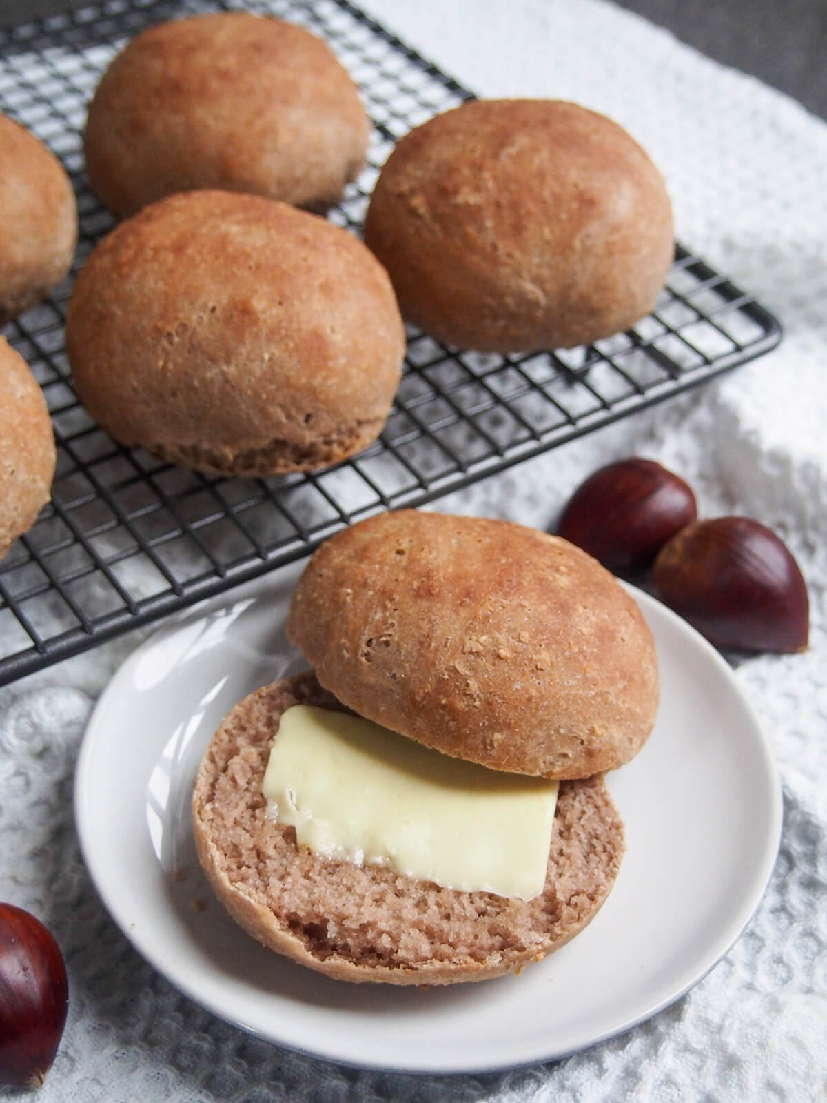 chestnut bread roll on plate with butter on lower half