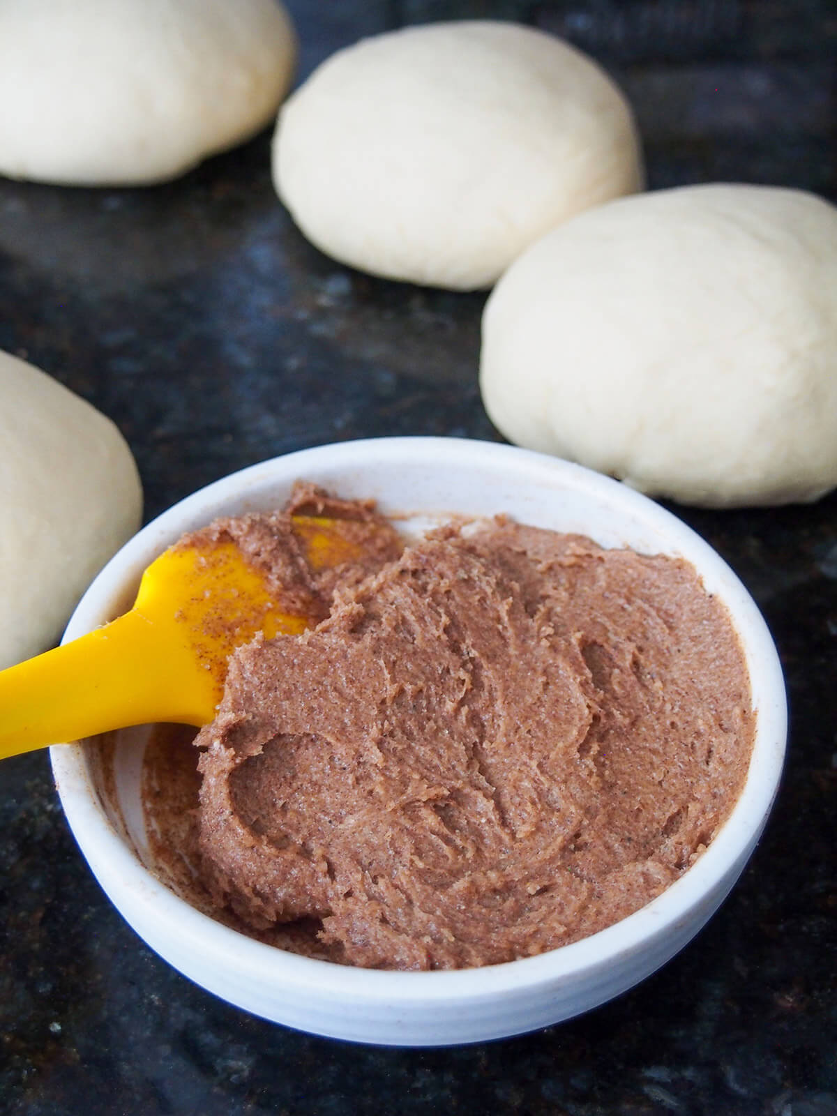 dish with sweetened cinnamon butter for filling with balls of bread dough behind
