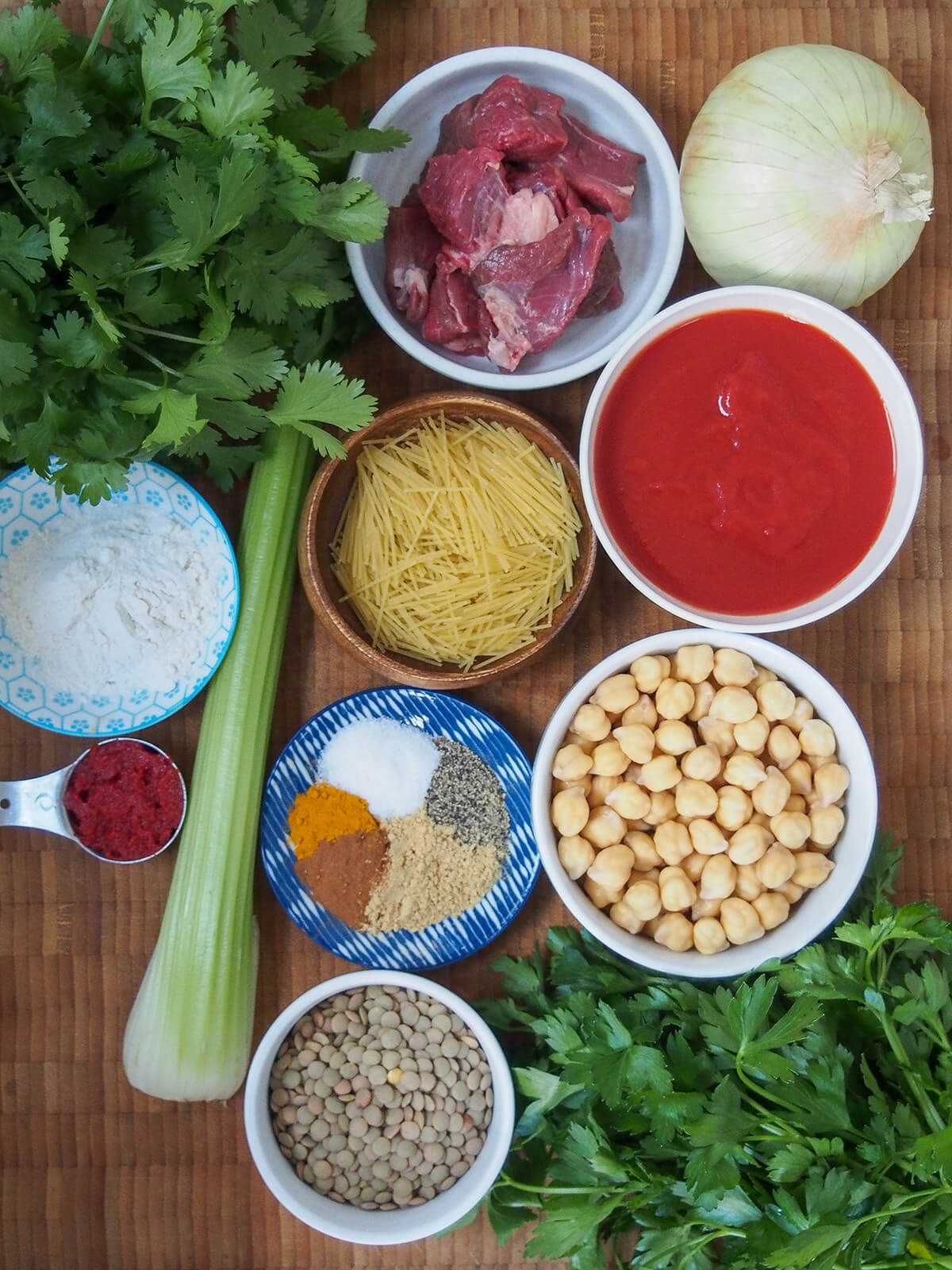 bowls with lentils, chickpeas, tomato, pasta, lamb and spices with herbs to side