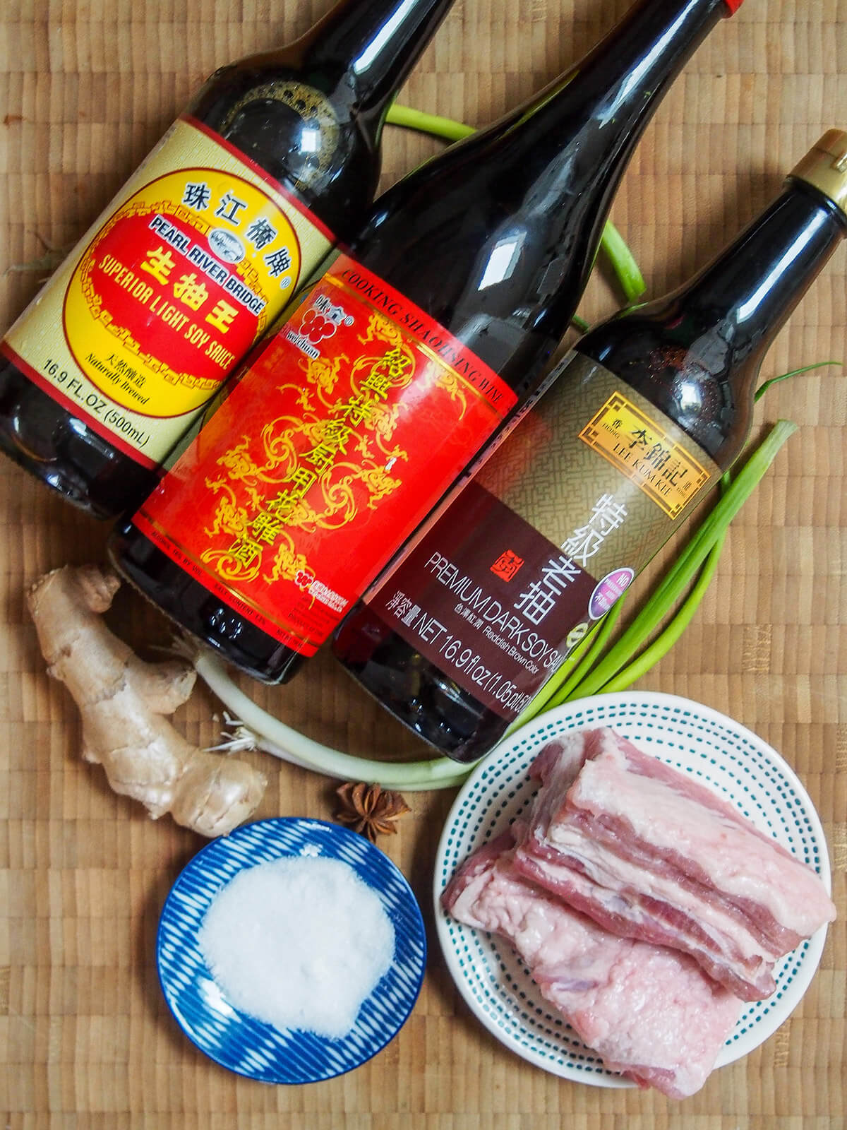 bottles of light and dark soy, shaoxing wine, pork belly, sugar, ginger, green onions and star anise