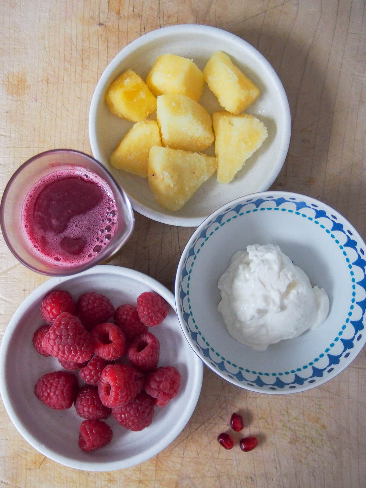 bowls with raspberries, pineapple, yogurt and pomegranate juice