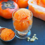 glass of persimmon ginger sorbet with scoop to side