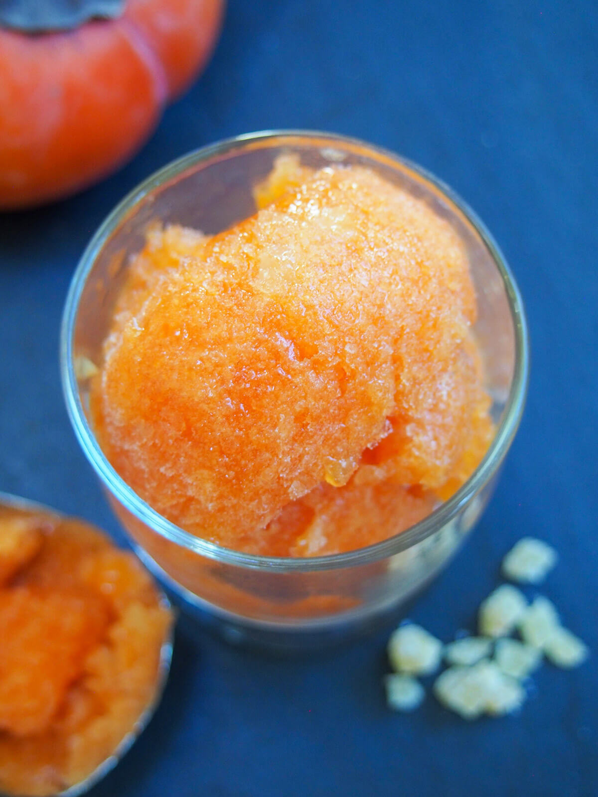 This delicious persimmon ginger sorbet is easy to make and both looks and tastes great. The zingy ginger compliments the smooth, fragrant persimmon perfectly. glass of persimmon ginger sorbet from overhead